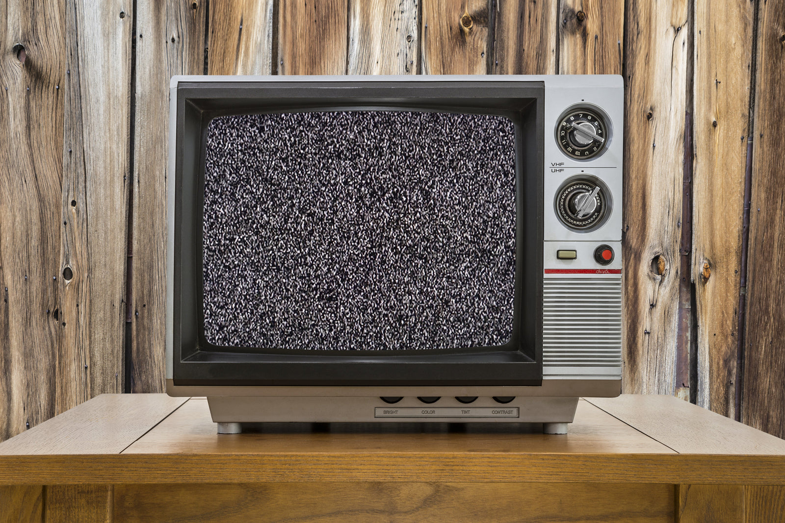 Person wiping a large flat-screen TV with a microfiber cloth, the safe way to clean a TV screen without damaging its anti-glare coating