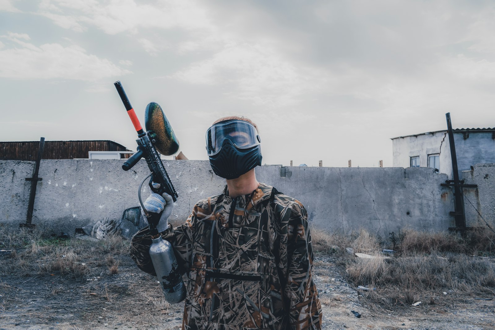 Paintball player in a full-face mask aiming a marker — sealed masks fog up fast without anti-fog protection