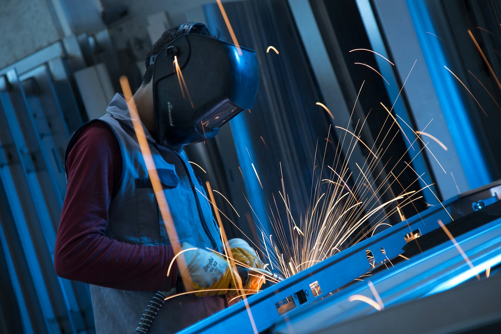 Welder using a torch with safety glasses and full PPE in an industrial workshop